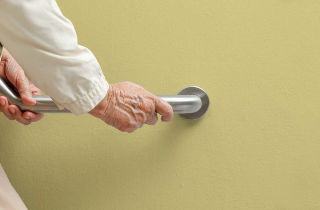 An older person using a handrail to assist themself