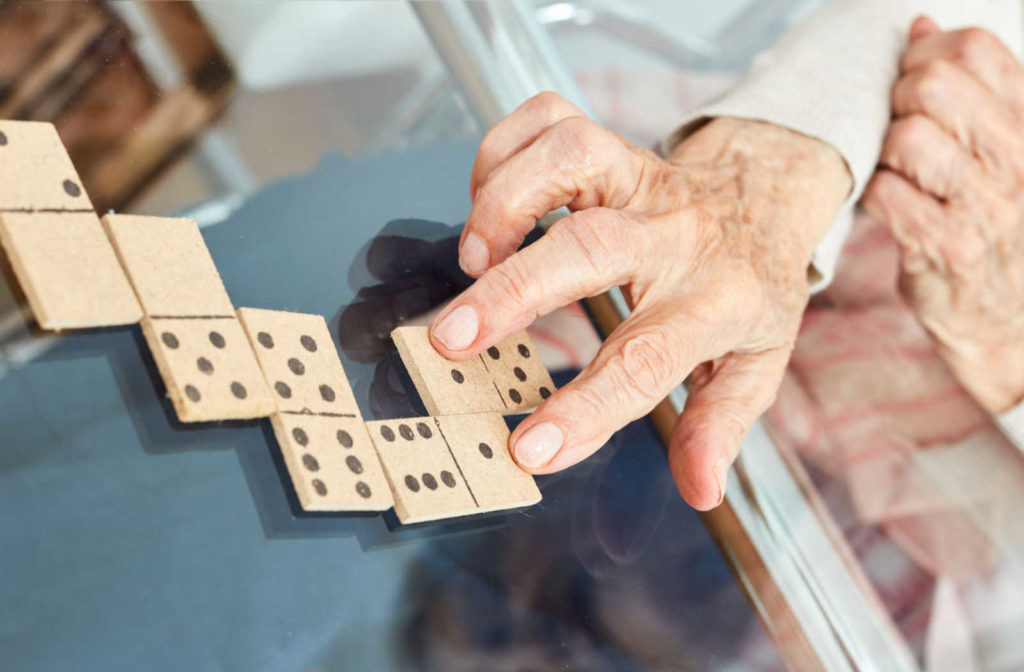 A senior's hand putting a domino next to another one.