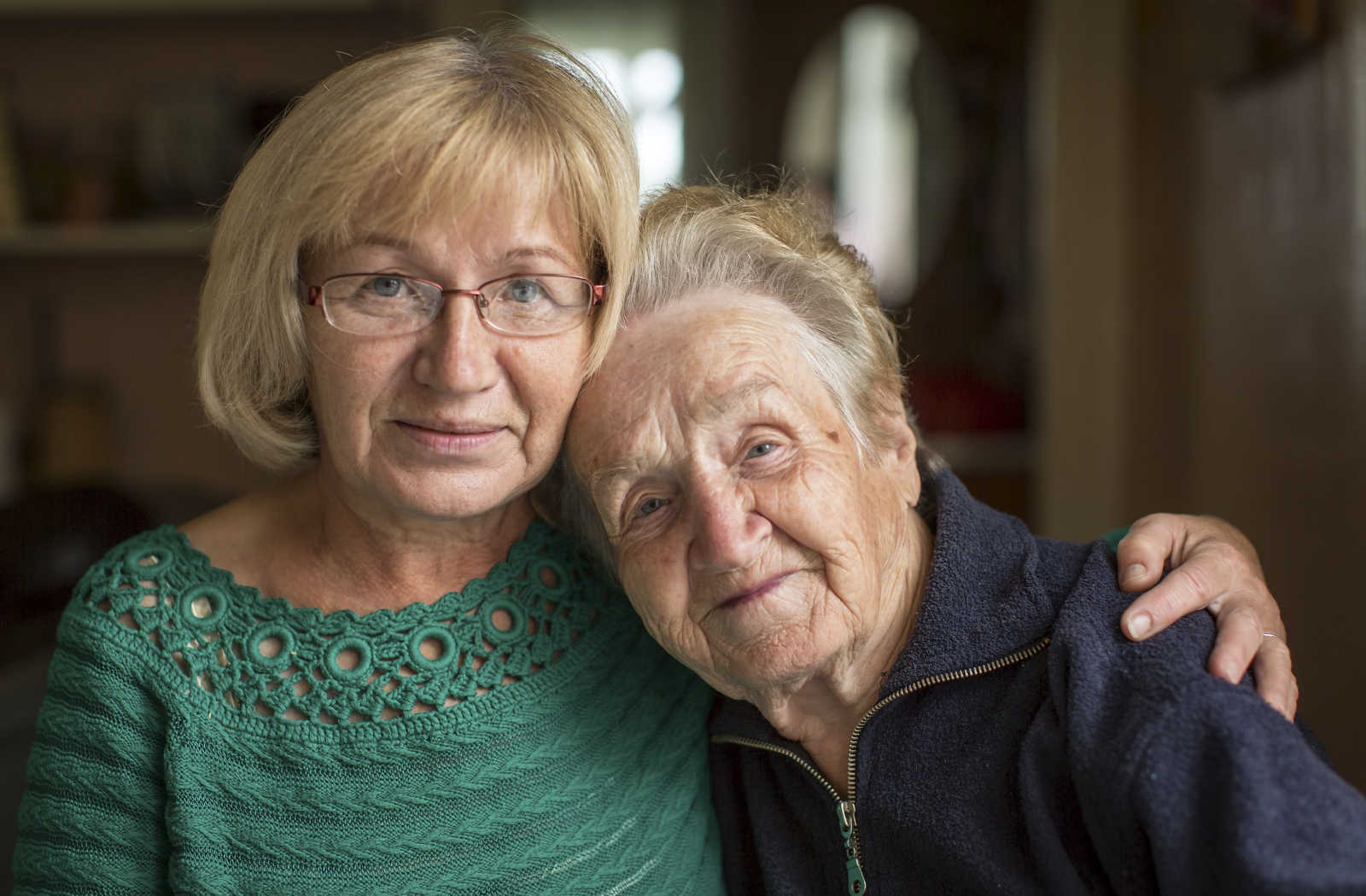 Mature woman putting an arm around her elderly mother.