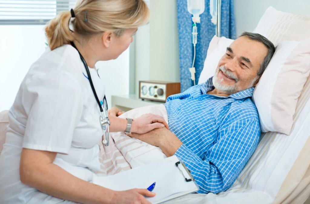 A nurse checks in on a senior resting in a hospital bed to evaluate their status as part of the transition to memory care