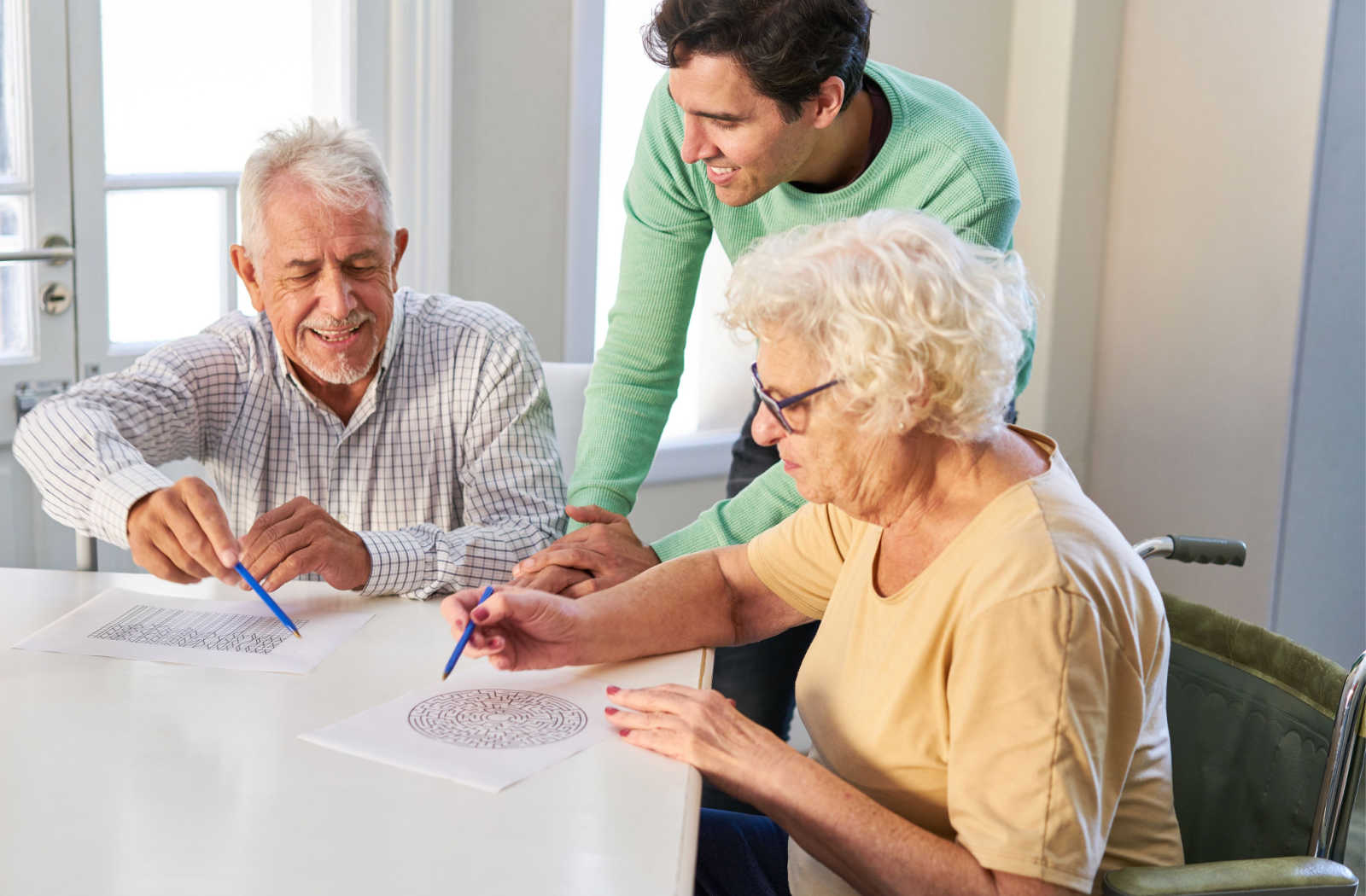 An Aid helping two seniors do a brain puzzle.