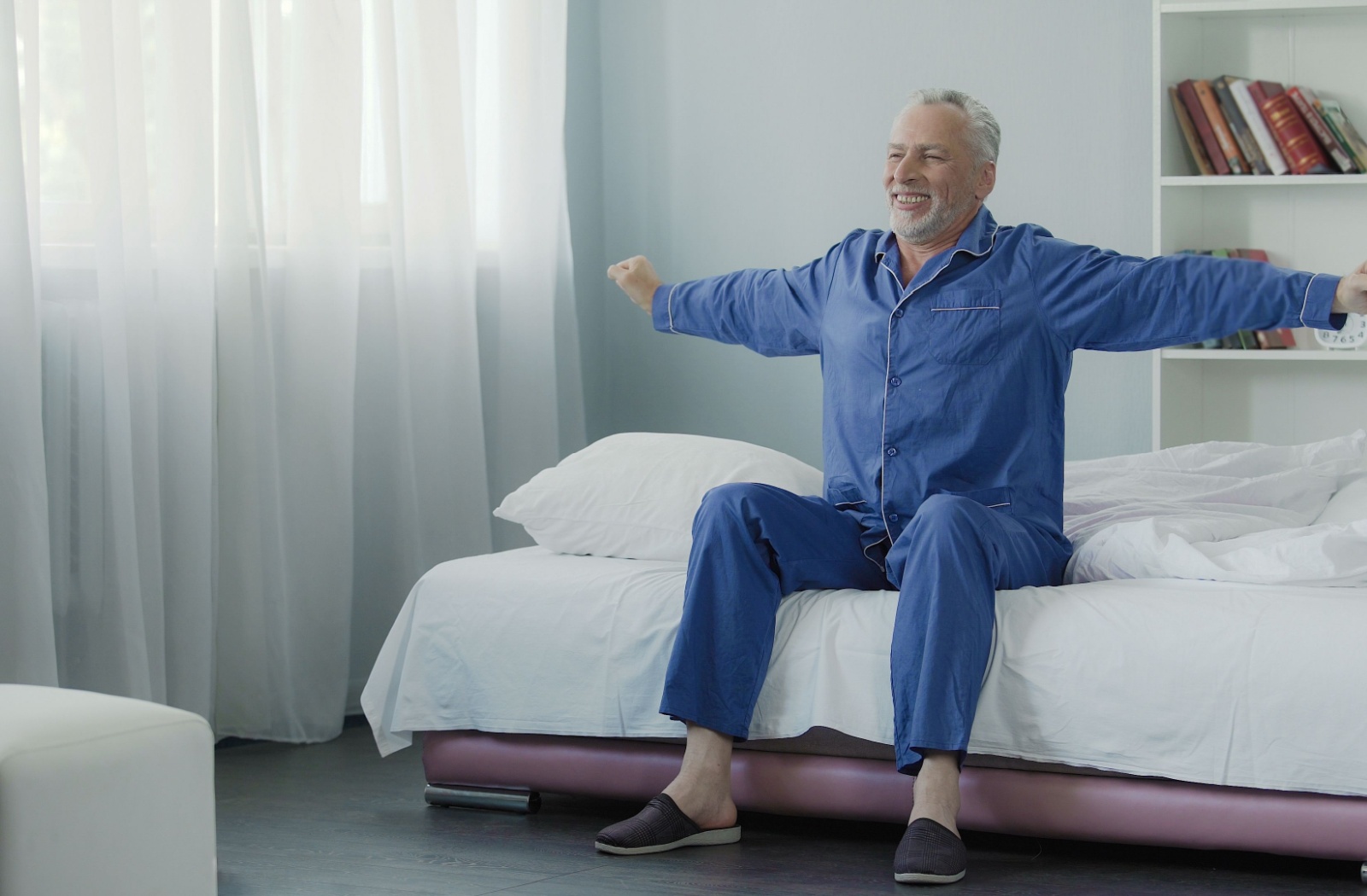 A happy senior stretches after performing their simple bed exercises to start the day.