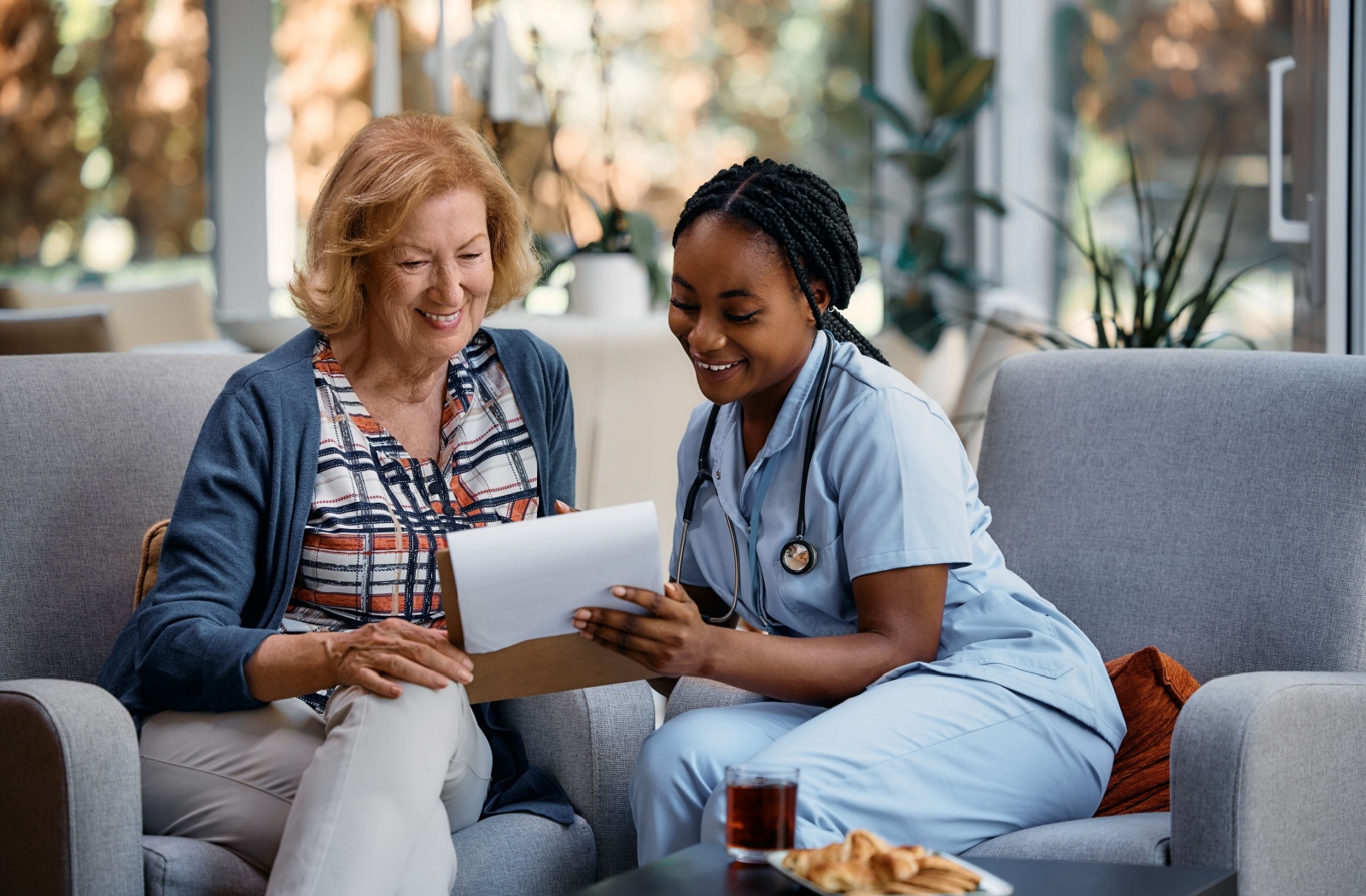 A nurse sitting down with and older adult in an assisted living community and going over a chart together.